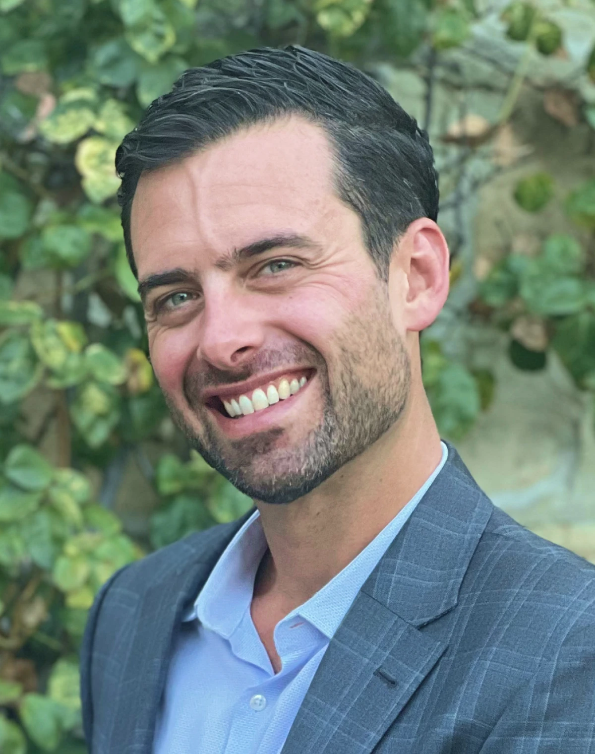Evan Dreyer, Head of Risk and Finance at TOLA, standing in front of foliage backdrop