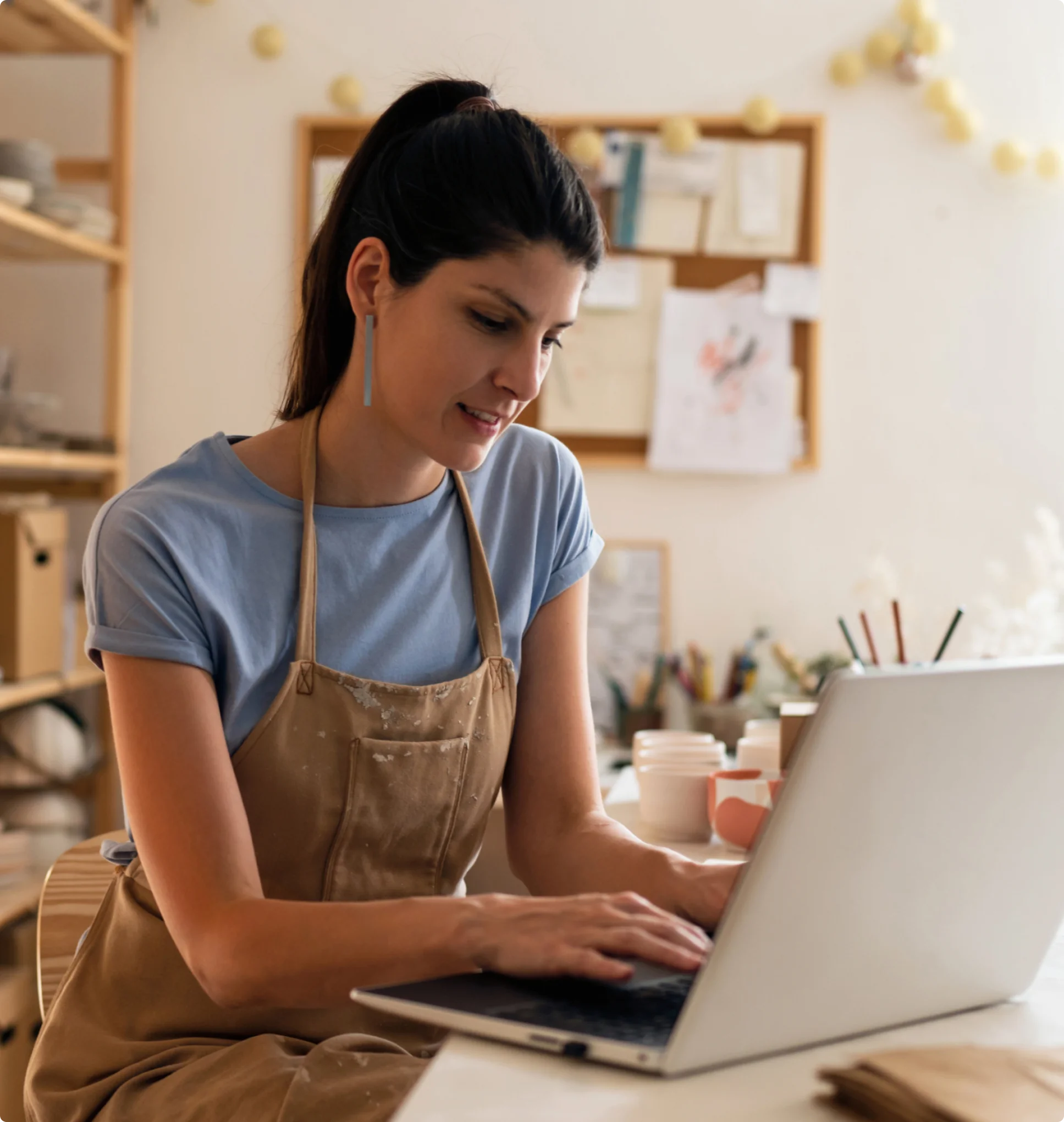 woman sitting at a work table in an apron in a studio